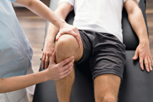physiotherapist examining a patient's knee for possible bursitis