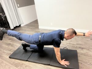 Man doing a bird dog exercise. One of the recommended exercises to promote core stability