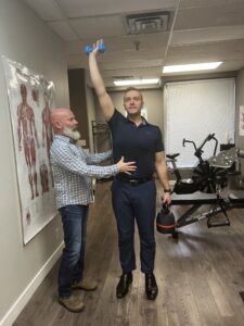Man working with Physiotherapist to build core strength using kettle bell lifts