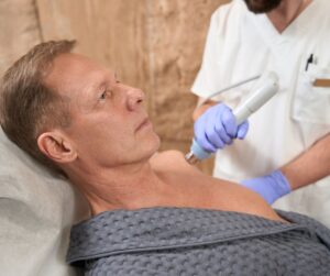 Physiotherapist doing a shockwave treatment on a man's frozen shoulder