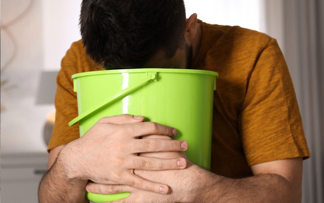 man with nausea vomiting in a bucket